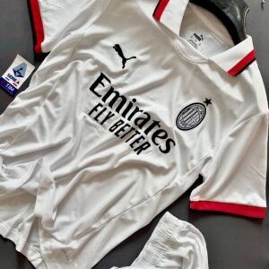AC Milan 2024 Away Jersey (Player Version) displayed on a flat surface alongside matching shorts. This official away kit features a crisp white design with subtle vertical pinstripes, complemented by red and black accents on the collar and sleeve cuffs. The AC Milan crest and black Puma logo are prominently positioned on the chest, with the Emirates Fly Better sponsor logo in the center. Made from high-performance fabric, this jersey combines style with functionality, ideal for AC Milan fans and players. 